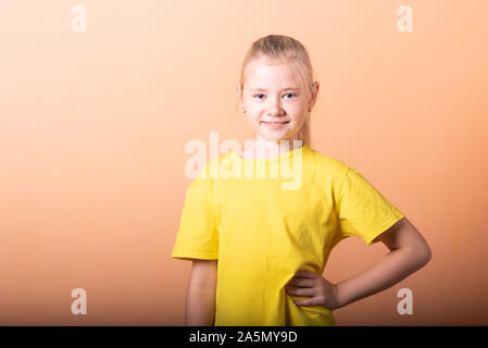 Das Mädchen legte ihre Hände auf ihren Hüften, auf einem hellen orange hinterlegt. Stockfoto