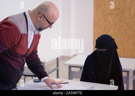 Männliche Professor für Architektur erklären Lektion weibliche Student trägt die Niqab und Interagieren mit ihr im modernen Klassenzimmer zu muslimischen. Helfen eines Studenten Stockfoto
