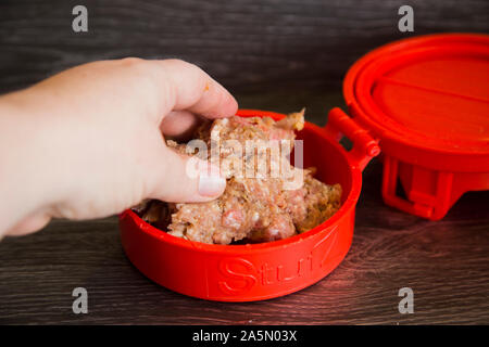 Aus rotem Kunststoff burger Stopfer. Rind und Schwein Hackfleisch Frikadellen mit knusprigem Speck gefüllte Brocken der Colby Käse. Zeigt drücken Sie im Einsatz mit Rohstoffen Stockfoto