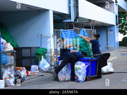 Bangkok, Thailand - 20. Oktober 2019: Drei weibliche Arbeitnehmer sind die Trennung verwendete Kunststoff Behälter, Dosen aus Metall und Verpackung in grün Tasche für Stockfoto