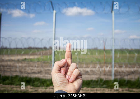 Mittelfinger auf einer Hand ein Demonstrant auf Grenzzaun zwischen Rastina (Serbien) & Bacsszentgyorgy (Ungarn). Diese Wand wurde in 20 gebaut Stockfoto