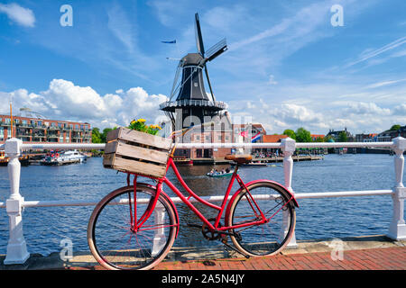 Altes Fahrrad auf der Brücke mit dem De Adriaan Wndmill im Hintergrund, Haarlem, Niederlande Stockfoto