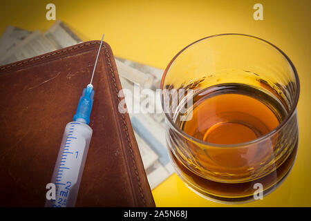 Glas mit Whiskey und eine Spritze auf einem Couchtisch aus Glas Stockfoto