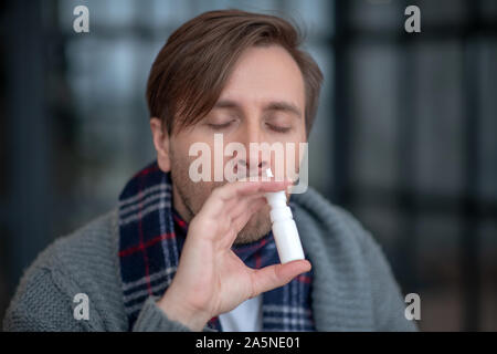 Mann mit nasenspray Leiden vom Niesen Stockfoto