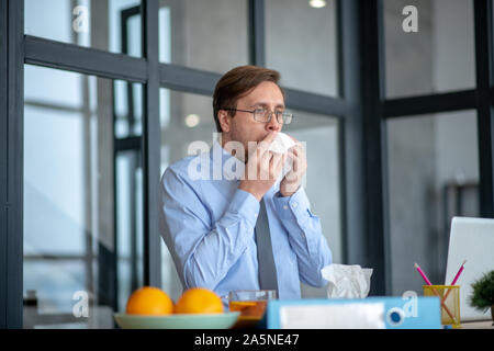 Unternehmer den ganzen Tag Niesen bei der Arbeit und Gefühl von Schwindel Stockfoto