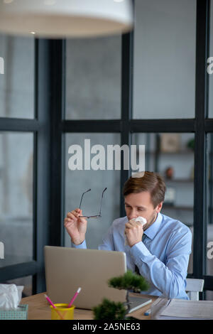 Unternehmer, die Brille abnehmen, während den ganzen Tag niesen Stockfoto