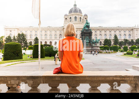 Junge weibliche Touristen auf dem Hintergrund der Maria Theresia Square in der Nähe von Museum of Natural History in Wien sitzen. Stockfoto