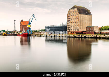 Panoramablick auf die kommerziellen Hafen von Stralsund mit Kränen, Lagerhallen und Tugboat. Stockfoto