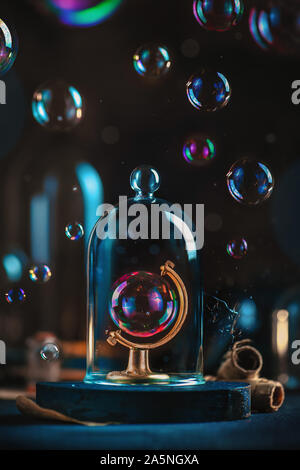 Soap Bubble in einem Globus Rahmen unter einer Glaskuppel. Ökologie und Klimawandel Konzept. Zerbrechliche Erde noch Leben mit Kopie Raum Stockfoto