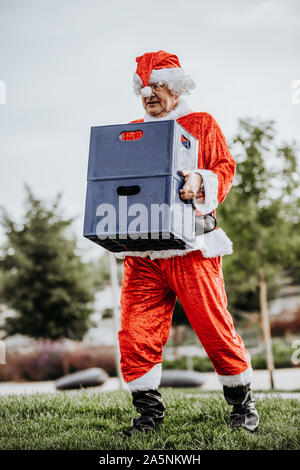 Vertikale Foto von Papa Noel ohne Bart laden mit zwei Kästen Bier. Weihnachten Stockfoto