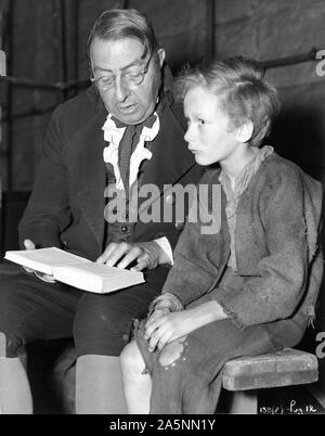 KENNETH DOWNY als Arbeitshaus Master und John Howard Davies als Oliver Twist 1948 Regisseur David Lean Roman CHARLES DICKENS auf offener Satz während der Dreharbeiten lesen das ursprüngliche Buch Foto von Charles Trigg Cineguild/Allgemein Film Distributors (GFD) Stockfoto