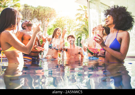 Multi-ethnischen Gruppe von Freunden toasten Champagner auf eine Pool Party Stockfoto