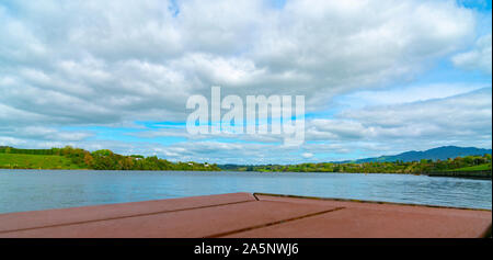 Blick über den Lake Karapiro von der Aussichtsplattform in der Nähe von Rudern mit fernen Eigenschaften auf der anderen Seite. Unter bedecktem Himmel. Stockfoto