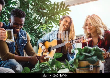 Gruppe der multirassischen Freunde, Spaß haben, Gitarre spielen Bier trinken im Urlaub Stockfoto