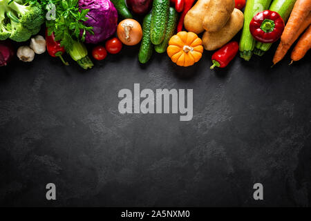 Kulinarische Hintergrund mit frischen, rohen Gemüse auf einem schwarzen Küchentisch, gesunde, vegetarische Essen Konzept, flach Zusammensetzung, Ansicht von oben Stockfoto