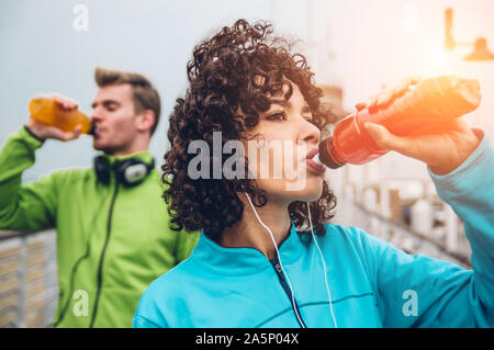 Mann und Frau trinkt Energy Drink von der Flasche nach Fitness Sport Übung