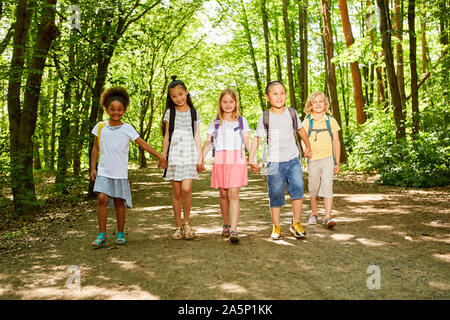 Gruppe der multikulturellen Kinder mit Rucksack auf Wandertag in der Natur Stockfoto