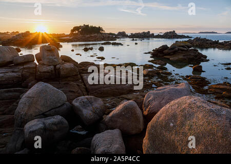 Sonne hinter Île de Costaérès, Ploumanac'h, Côte de Granit Rose, Bretagne, Frankreich Stockfoto