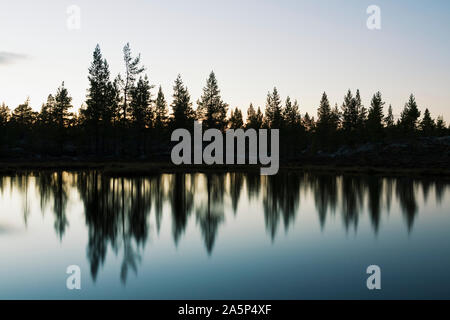 Silhouetten von Bäumen im See widerspiegeln Stockfoto