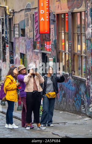 Asiatische Touristen fotografieren und Instagram Fotos von Graffiti und Street Art in Hosier Lane Melbourne, Victoria, Australien. Stockfoto