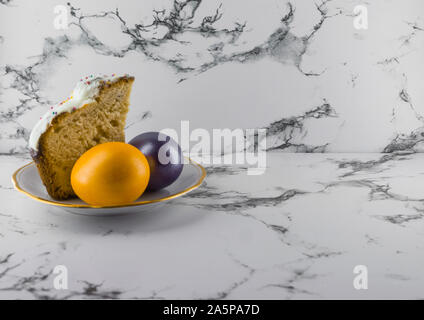Marmor Ostern Hintergrund mit bemalten Ostereiern und Ostern Kuchen auf eine Platte. Stockfoto