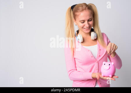 Glückliche junge blonde nerd Frau einfügen Münze in piggy Bank Stockfoto