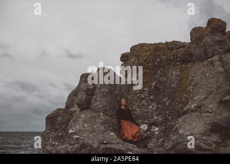 Junge Frau steht auf Felsen Stockfoto