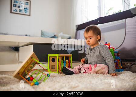 Süße kleine Baby mit Spielzeug spielen im Wohnzimmer auf dem Teppich. Stockfoto