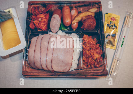 Jeju Island, South Korea, September 06, 2019: Nahaufnahme der offenen koreanischen Brotdose mit Spam, Würstchen, Kimchi und marinierten daikon als Beilage Stockfoto