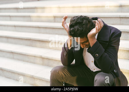 Junge schöne Indische Mann. Sitzt traurig auf den Stufen Stockfoto