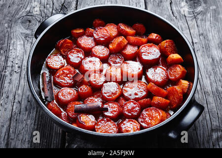 Thanksgiving kandierten Yamswurzeln, Süßkartoffeln zubereitet mit Zimt, brauner Zucker und Butter in einem schwarzen Keramik Teller, horizontale Ansicht von oben Stockfoto