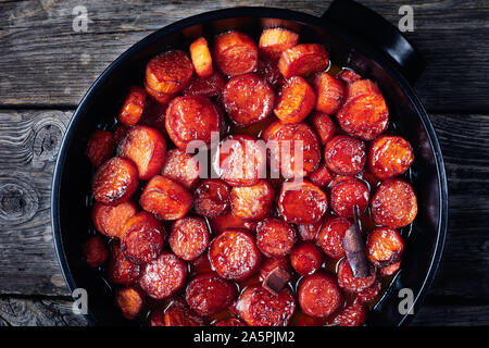 Thanksgiving kandierten Yamswurzeln, Süßkartoffeln zubereitet mit Zimt, brauner Zucker und Butter in einem schwarzen Keramik Teller, horizontale Ansicht von oben, flatlay Stockfoto