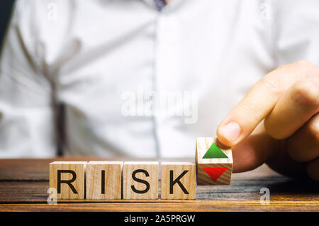 Geschäftsmann setzt Holzblöcke mit dem Wort Risiko und die Pfeile nach oben und nach unten. Business Risk Management Konzept. Vorhersage und Planung. Risikobewertung Stockfoto