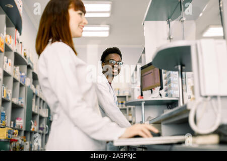 Zwei Apotheker Mann und Frau Kontrolle Informationen über Medikamente auf dem Computer zusammen, moderne Apotheke Stockfoto