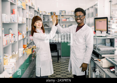 Weibliche und männliche Apotheker in der Apotheke. Afrikanischer Mann und kaukasische Frau fünf, arbeiten an modernen Pharmazie Stockfoto