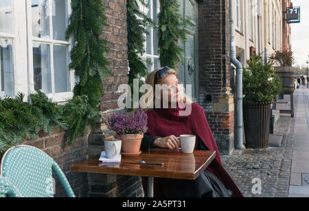 Frau sitzt an einem Tisch in Cafe im Freien Stockfoto