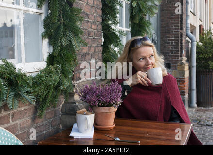 Frau sitzt an einem Tisch in Cafe im Freien Stockfoto