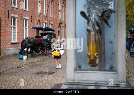 Brügge, Belgien, 11. Oktober 2019: Pferdekutsche mit Touristen und Trinkbrunnen für Pferde im historischen Zentrum von Brügge, selektive konzentrieren. Stockfoto