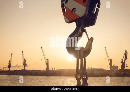 Haken eines Krans in einem Hafen bei Sonnenuntergang Stockfoto