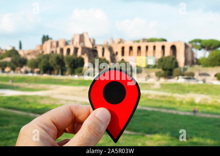 Nahaufnahme der Hand eines kaukasischen Mann hält eine rote Markierung auf die Überreste des Circus Maximus in Rom, Italien, mit dem Palatin in der backgro Stockfoto