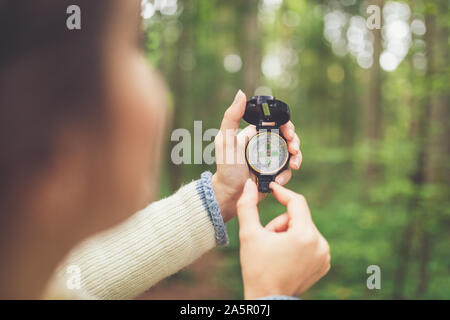 In der Nähe der weiblichen Händen hält Kompass gegen Wald Fußweg. Natur Orientierung Konzept. Stockfoto