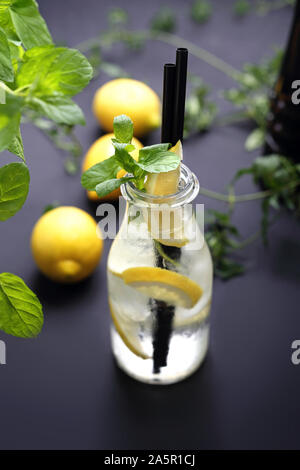 Wasser mit Zitrone, Wasser in einer Glasflasche mit Zitrone und Minze. Stockfoto