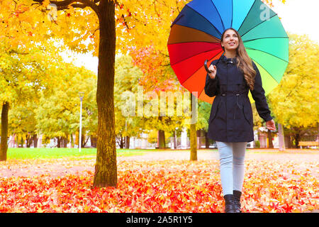 Herbst Saison. Junge Frau zu Fuß im Stadtpark unter bunten Regen Regenschirm. Stockfoto
