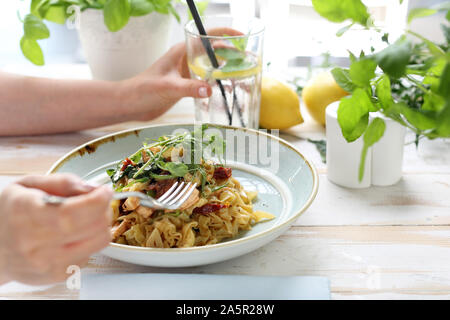 Spaghetti mit Lachs und getrocknete Tomaten. Die Frau isst ein leckeres Gericht Stockfoto