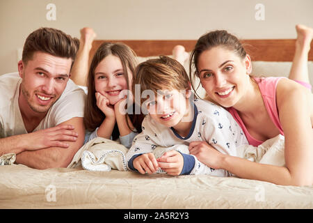 Glückliche Eltern mit zwei Kindern im Schlafanzug morgens im Bett Stockfoto