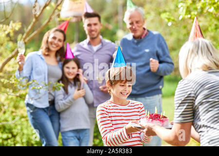 Oma gratuliert Enkel Kind auf einem Geburtstag Kuchen auf einer Gartenparty Stockfoto