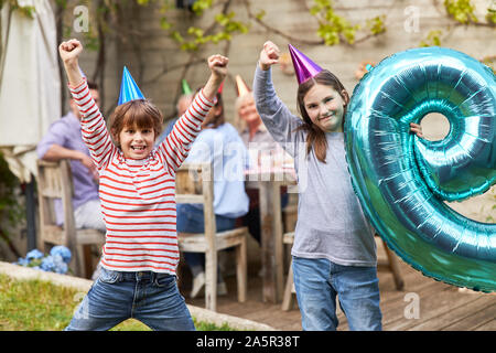 Geschwister zusammen feiern Kindergeburtstag mit der Familie im Sommer im Garten Stockfoto