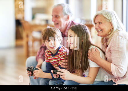 Großeltern und Kinder mit Spielkonsole Zusammen Spass haben in video game Stockfoto