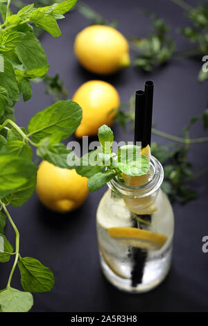 Kalte Getränke. Wasser mit Zitrone, Wasser in einer Glasflasche mit Zitrone und Minze. Stockfoto