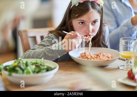 Hungrige Kinder essen Spaghetti mit Tomatensauce zum Abendessen Stockfoto